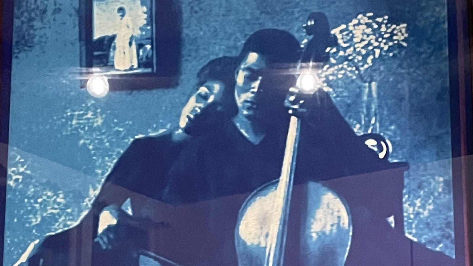 A Black man plays the cello softly as a woman leans on his shoulder at dusk, in a photograph in Lorenzo Baker's new work at MCLA. Press image courtesy of the artist
