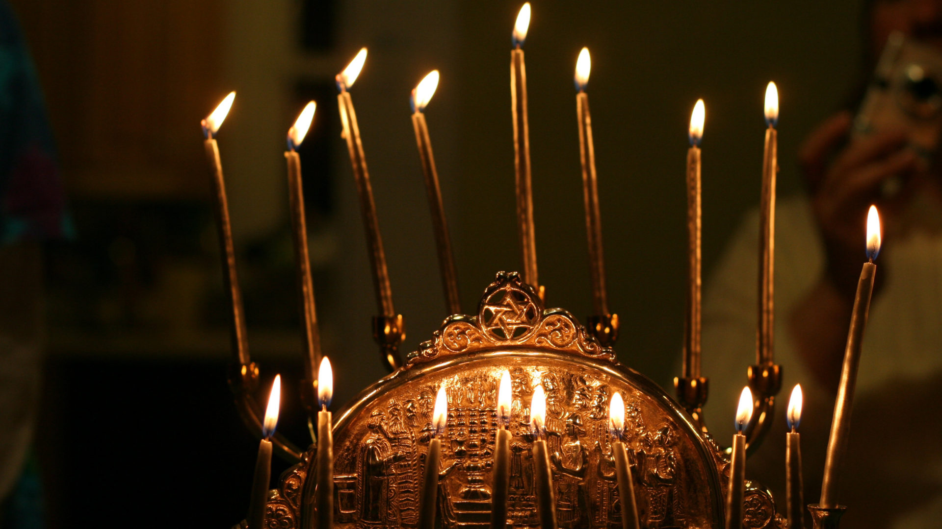 A menorah gleams in shades of copper and bronze in the candlelight. Creative Commons courtesy photo