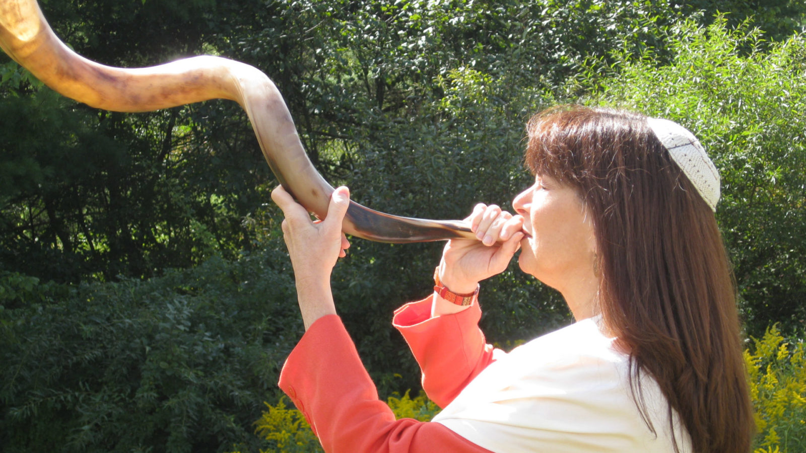 Rabbi Debbie Zecher, former Rabbi of Hevreh for many years, blows the shofar, a ram's horn, to call in Rosh Hashana.