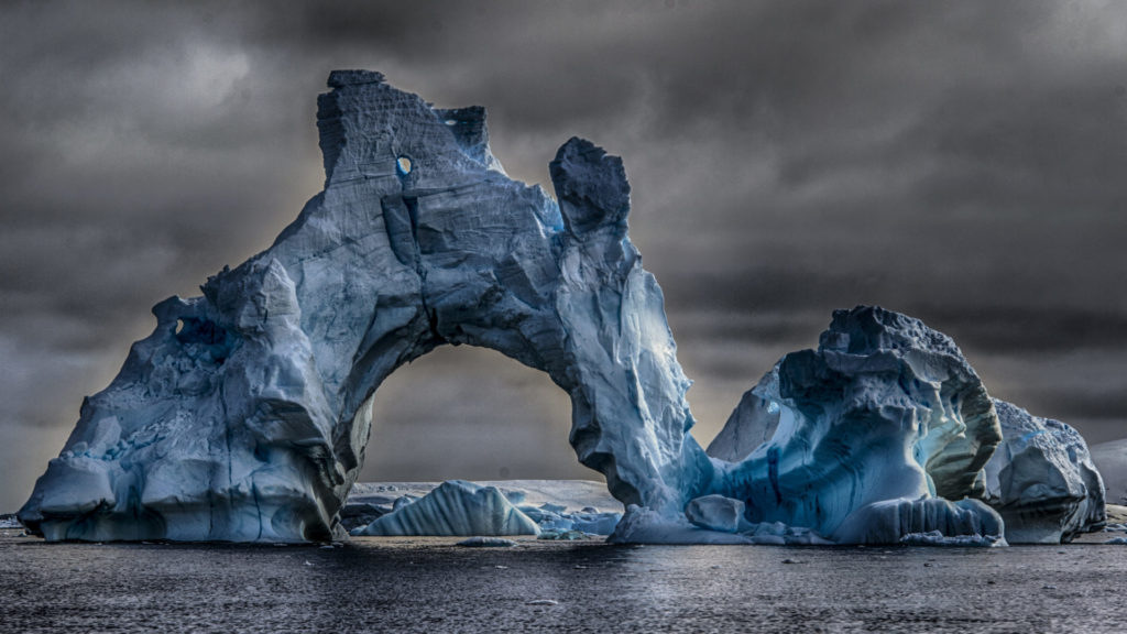 Deep blue icebergs arch over the water at Cape Tuxen. Press photo courtesy of Seth Resnick and Cassandra Sohn Gallery