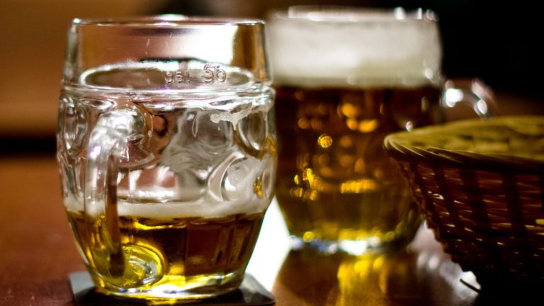 Beer mugs catch the light on a dark wood table. Creative Commons courtesy photo