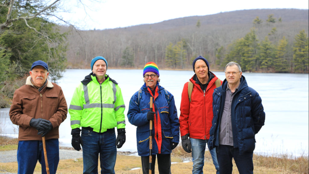 Q-Mob's hiking group stands on the shore of Lake Benedict in Beartown State Forest.