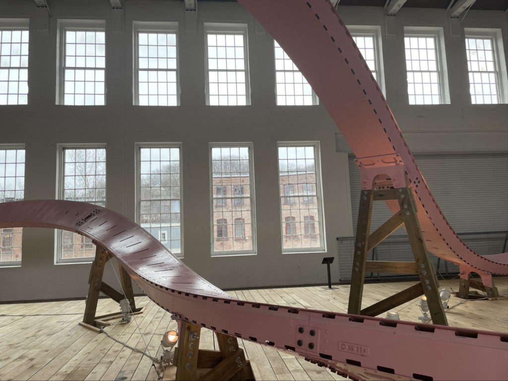 The pink roller coaster track loops across the old mill floor in EJ Hill's Brake Run Helix in Building 5 at Mass MoCA.