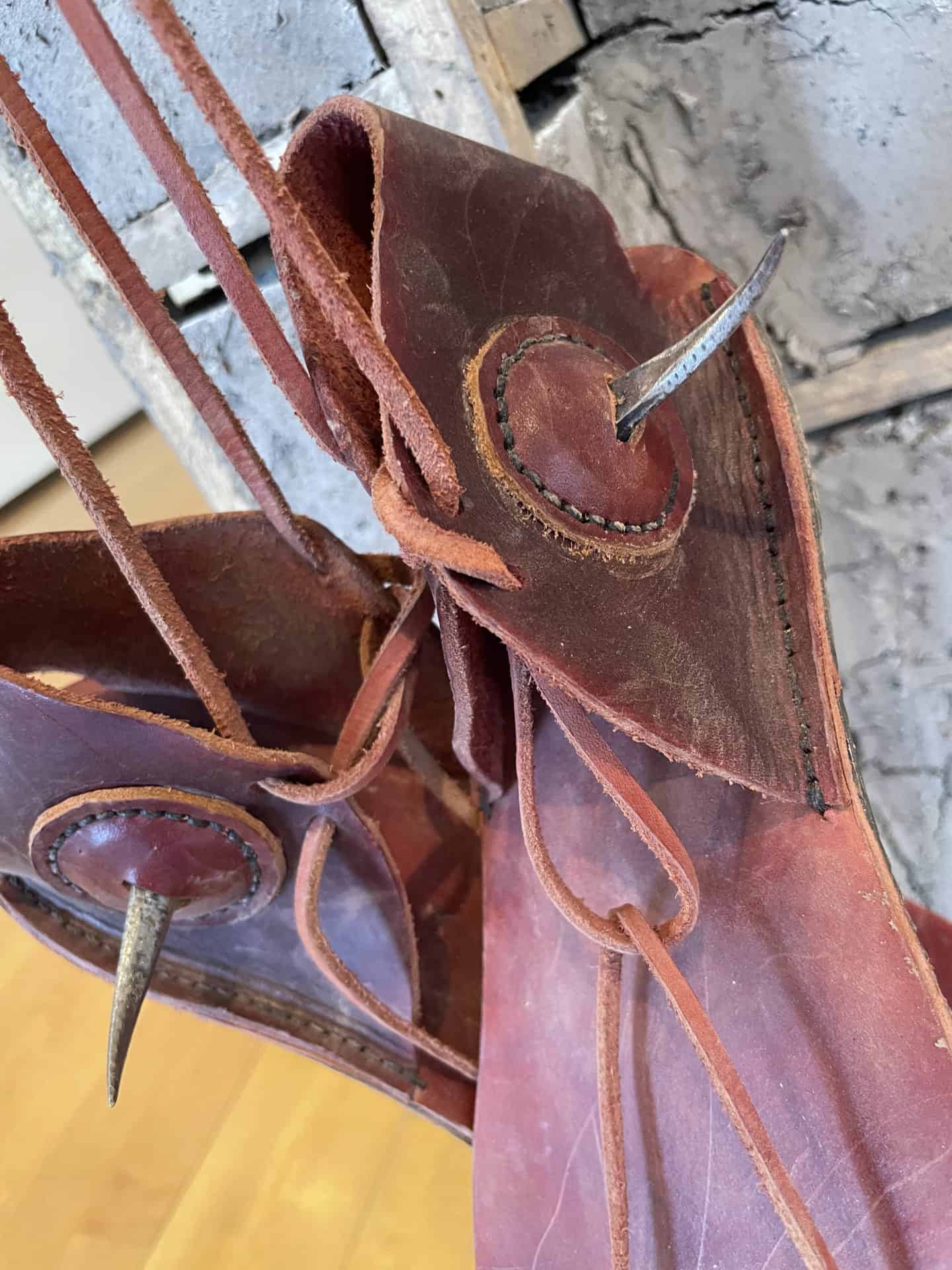 Leather boots with metal spurs hang in Armando Guadalupe Cortés’ 'Castillo' at Mass MoCA.