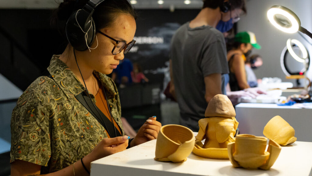 Visitors touch clay in Conversations with the Material World, an interactive art exhibit with sound and contact. Press photo courtesy of Catherine Monahon