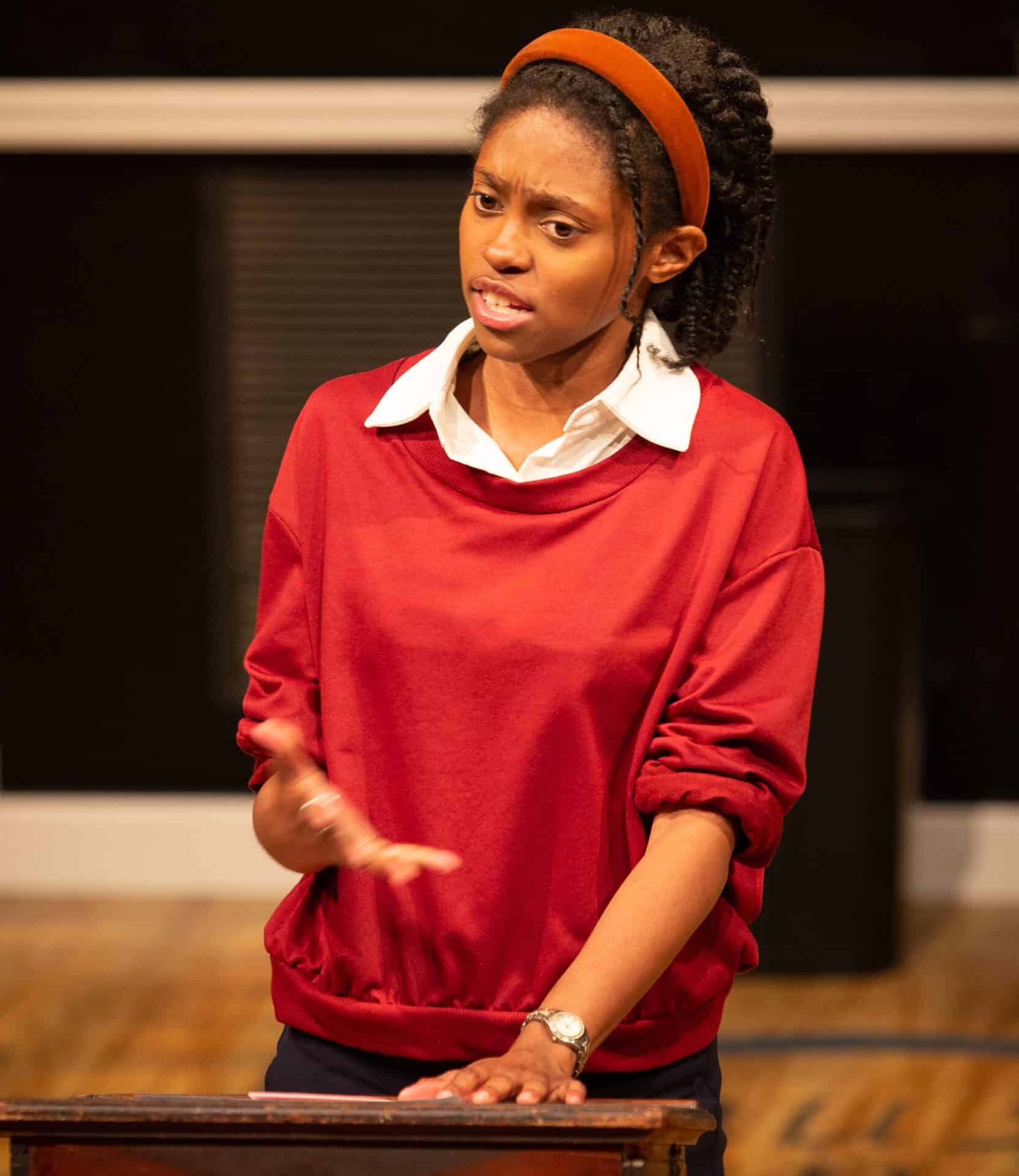 Zurie Adams speaks at a podium with serious confidence in WAM Theatre's production of What the Constitution Means to Me. Press photo courtesy of WAM Theatre