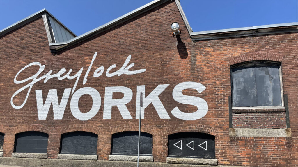 GreylockWorks shows waves of slanting brick wall on a sunny day.