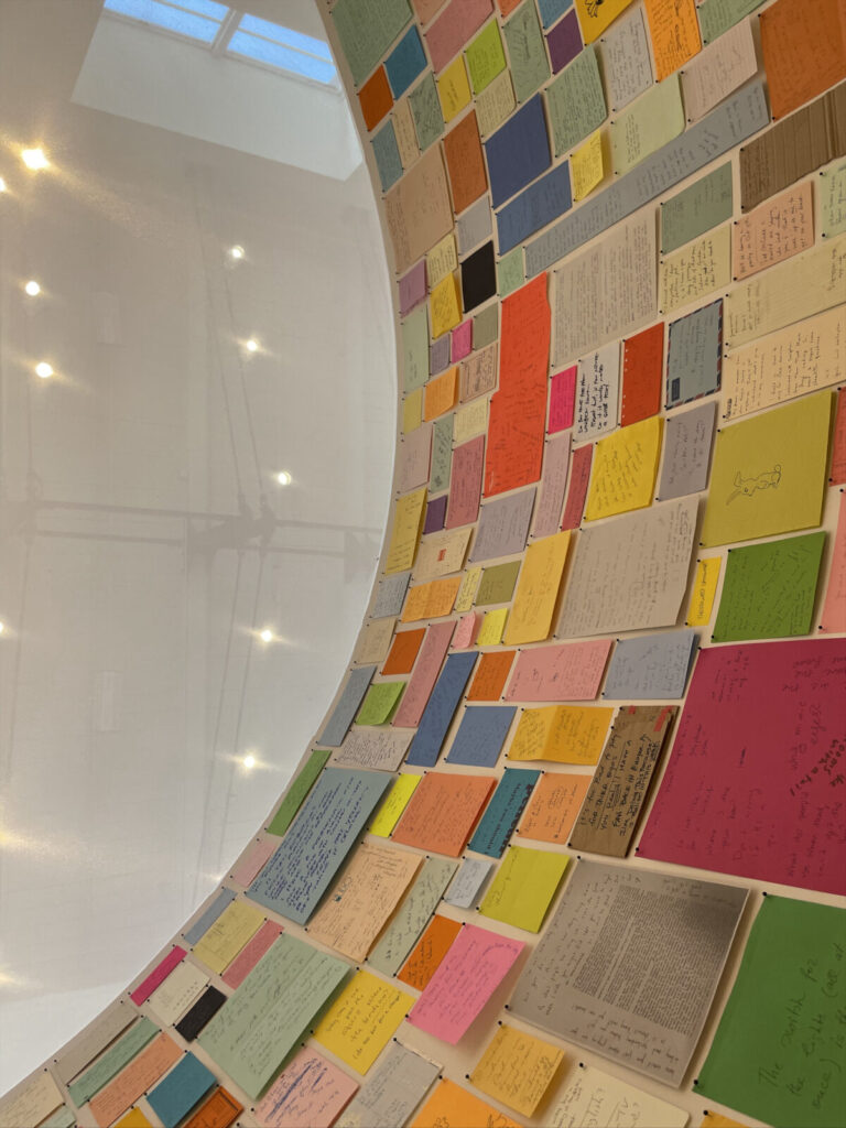 Joseph Grigely lines the walls of a round room with bright scraps of paper, notes people have written to him because they don't speak sign language, in 'In What Way Wham? White Noise and Other Works' at Mass MoCA.