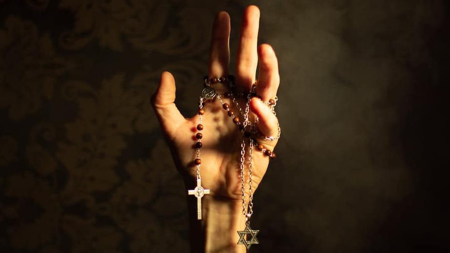 A hand holds a rosary and a Magen David, as LaPercha Theatre Company presents a contemporary play exploring a time of fanatical rule and resistance. Press photo courtesy of the Foundry