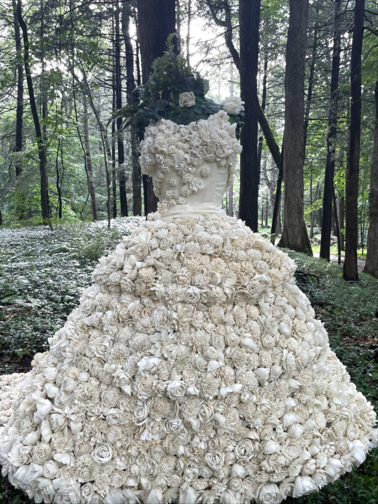 A gown of white roses stands on a forest path in Deborah Carter's sculpture Unbridled at the Mount.