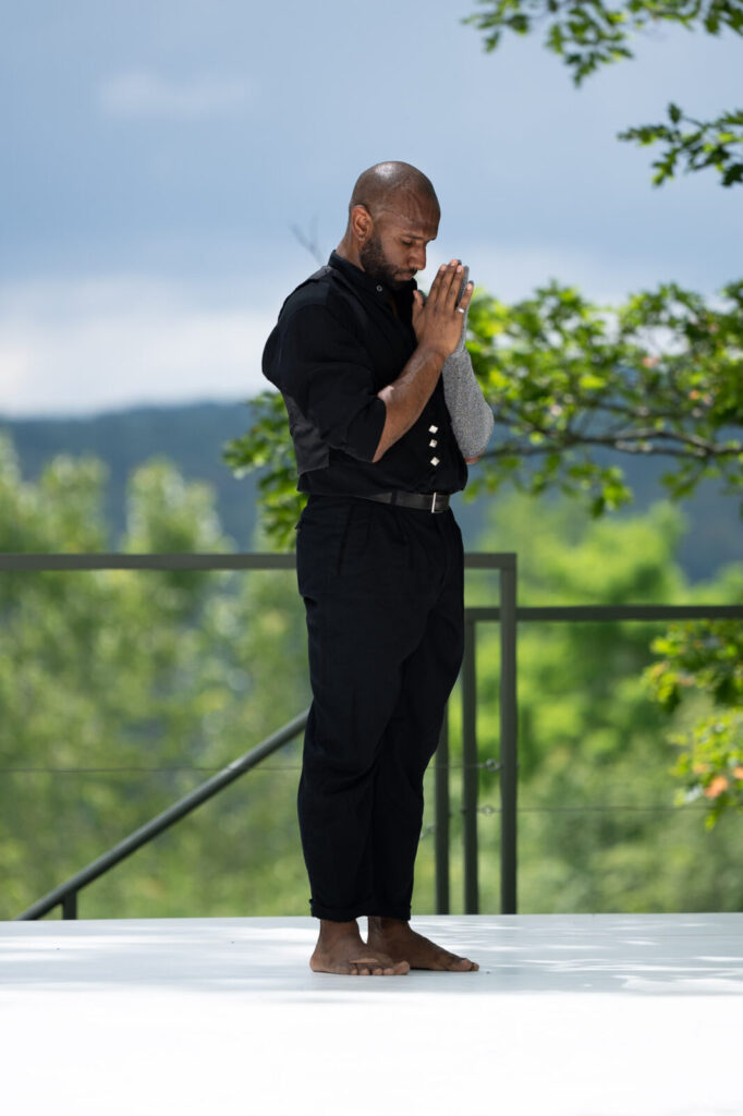 Nik Owens stands with his hands pressed together and his eyes closed as Kyle Marshall Choreography rehearses on the Leir outdoor stage. Photo courtesy of Jacob's Pillow Dance Festival
