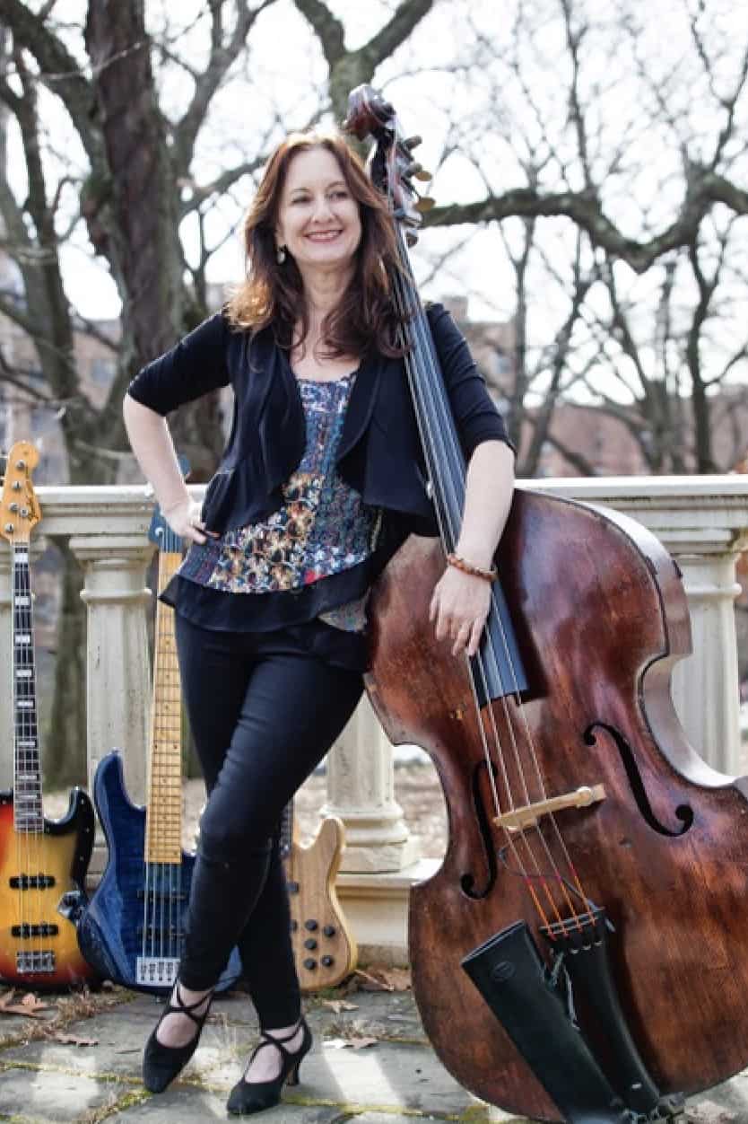 Internationally acclaimed bassist Mary Ann McSweeney leans an arm on her instrument. Press photo courtesy of the artist