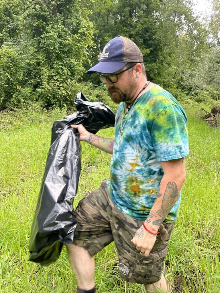 Justin Adkins, co-owner of Wild Soul River and member of Trout Unlimited, looks for trash along the Hoosic River in a cleanup near Harding Avenue in North Adams.