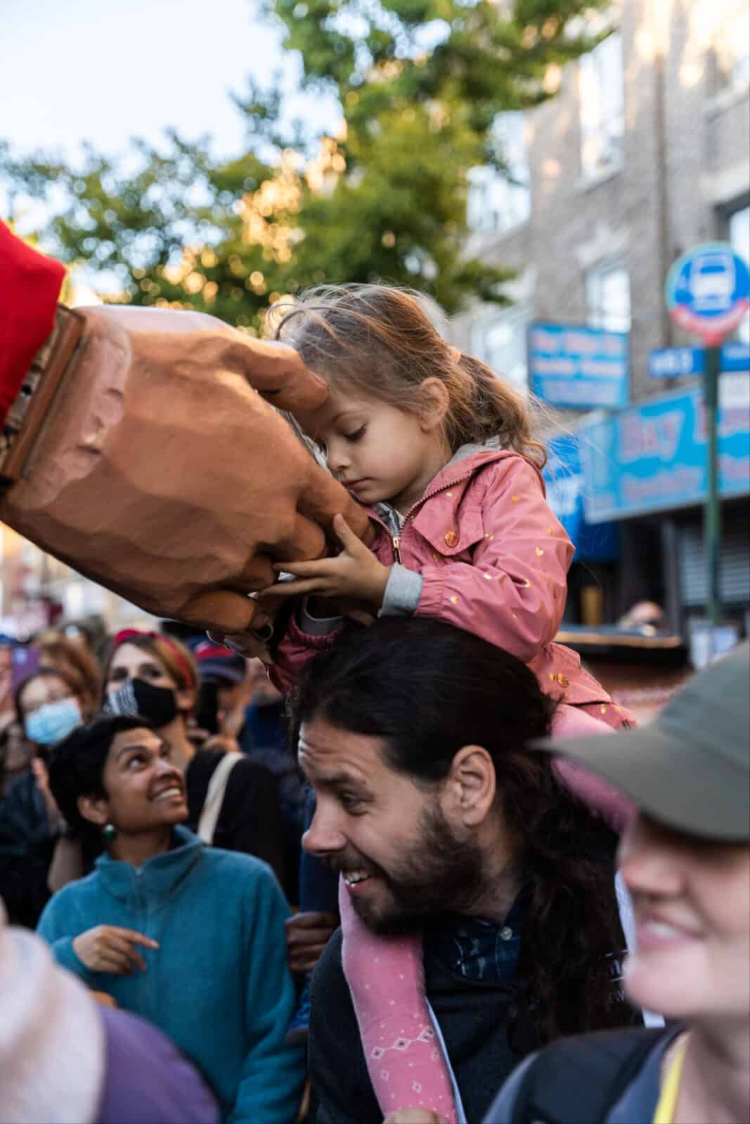 Amal meets a young girl sitting on her father's shoulders in Bay Ridge, N.Y. - Press photo courtesy of The Walk Productions