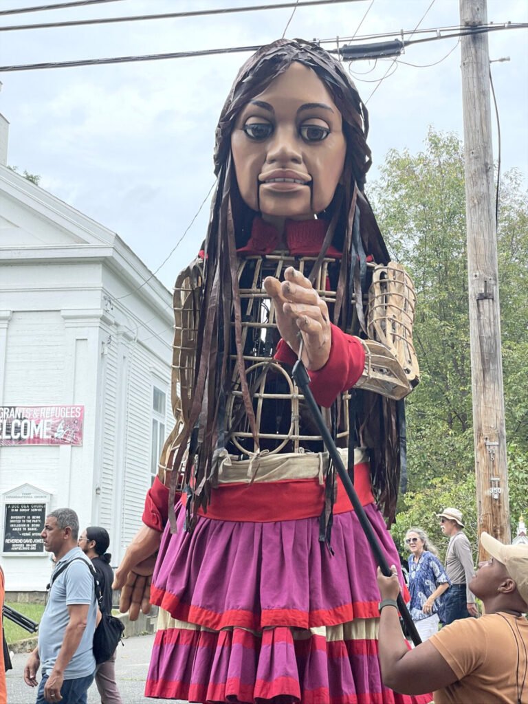 Amal - the 12-foot puppet, 10-year-old Syrian girl and global arts and human rights collaboration - dances in a procession in Ashfield.