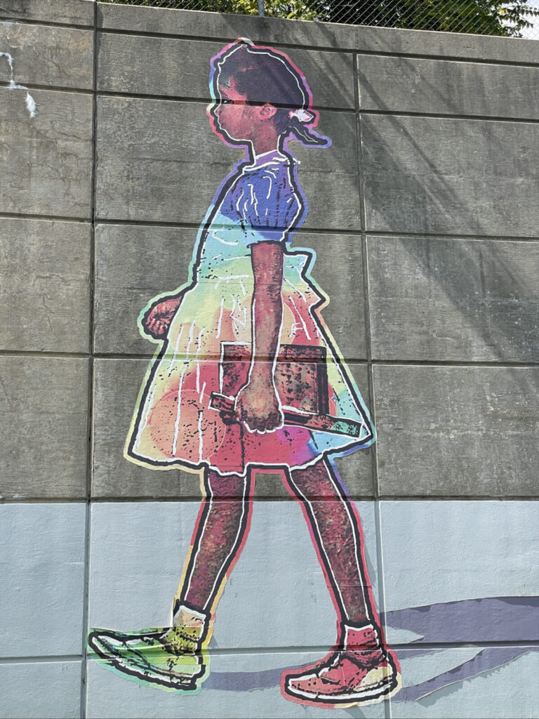 Ruby Bridges walks larger than life in rainbow color, in a mural on the Pittsfield overpass by Berkshire artist Maurice 'Pops' Peterson.
