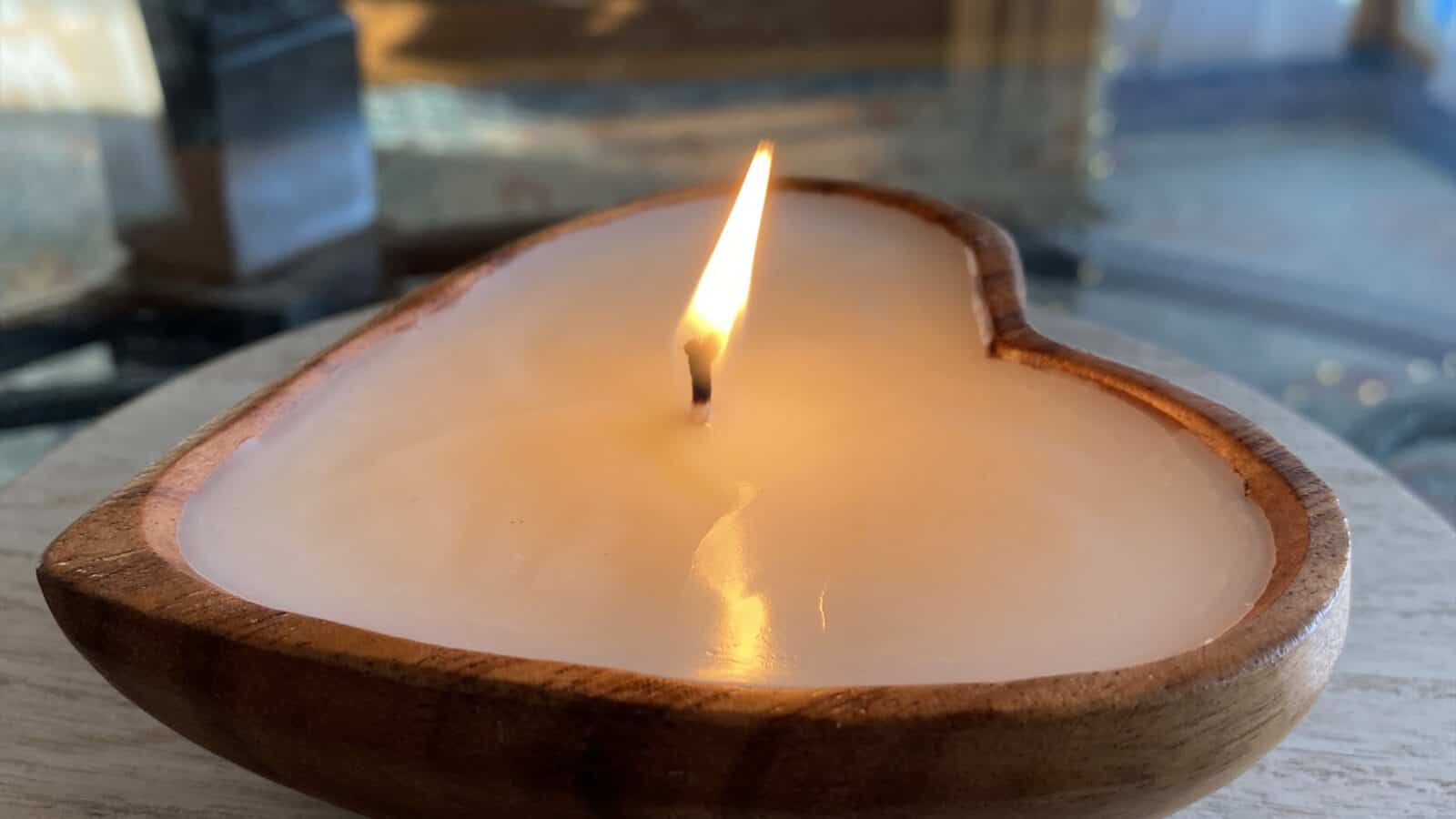 A Berkshire Candle Co. candle poured in a heart-shaped wooden bowl sits on a table in the sunlight. Photo courtesy of the artist