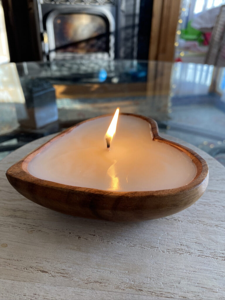 A Berkshire Candle Co. candle poured in a heart-shaped wooden bowl sits on a table in the sunlight. Photo courtesy of the artist