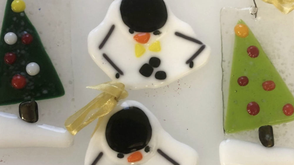 Fused glass ornaments form snow men and evergreen trees at Mendel's stained glass studio. Press photo courtesy of Lisa Mendel