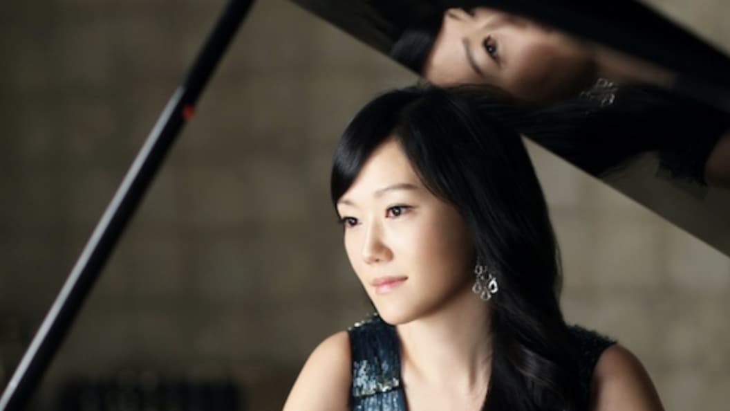 The Clark's Performing Artist in Residence, Jeewon Park, sits near her piano, refledted in the lid. Press photo courtesy of the museum
