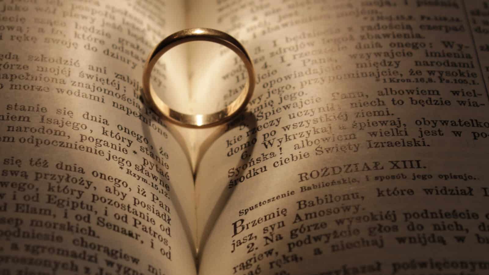 A ring holds open the pages of a book, casting a heart-shaped shadow. Creative Commons courtesy photo