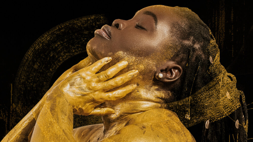 Internationally acclaimed Afro-Cuban jazz vocalist Dayamé Arocena touches her cheek with hands coated in a rich golden paint or clay. Press photo courtesy of Mass MoCA